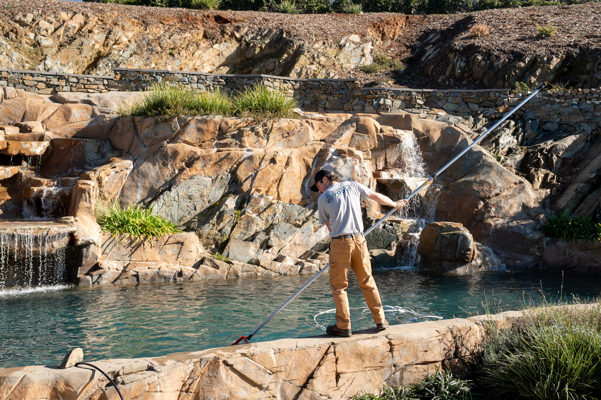 Woody's Pools tech brushing and vacuuming a pool