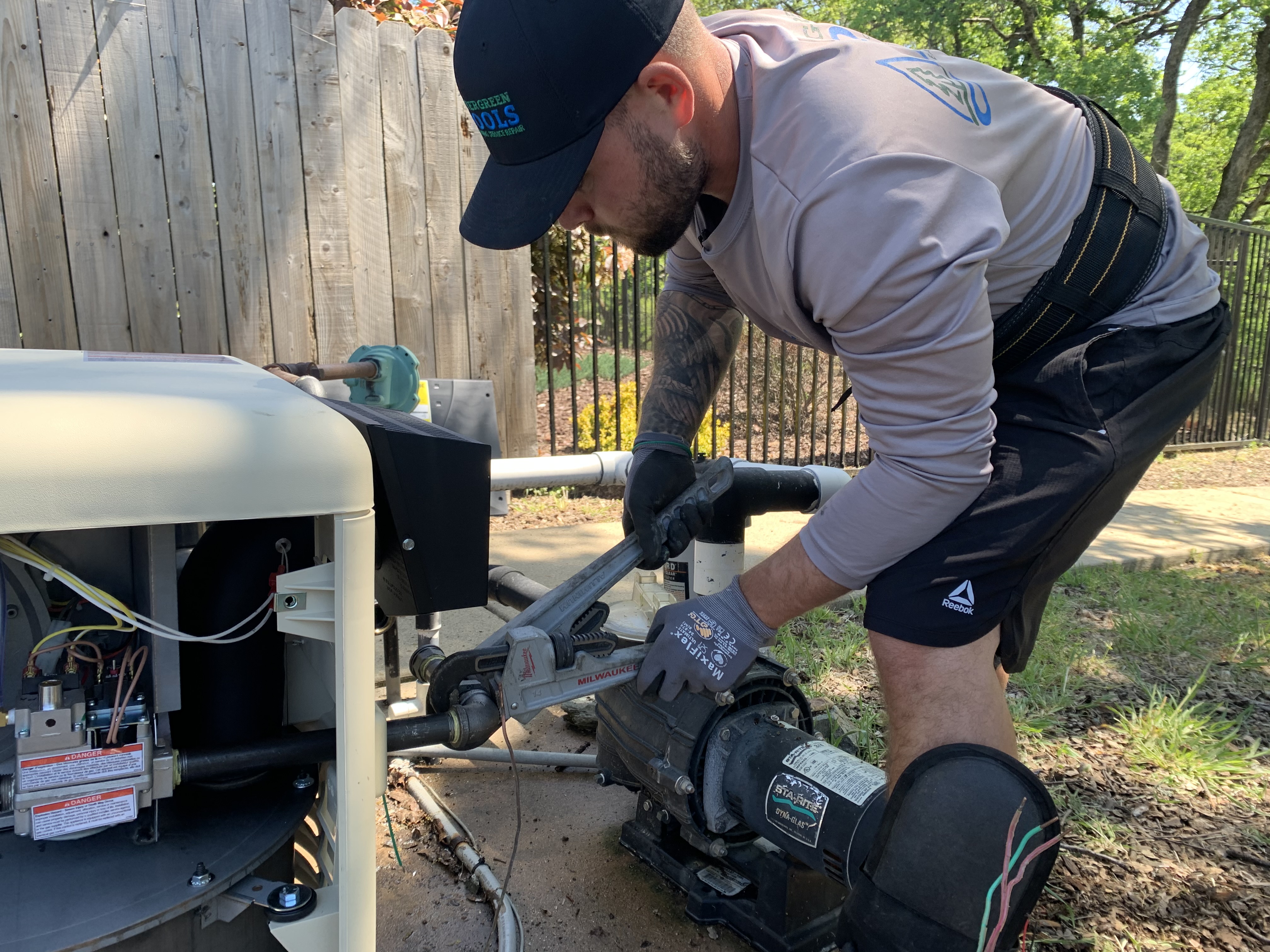 Woody's Pools tech servicing pool equipment with hose